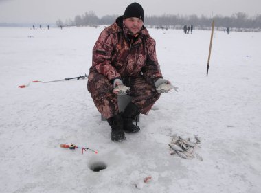 Balıkçı yakalanan balık kış boyunca balığa Dinyeper Kiev, Güney Köprüsü yakınlarında üzerinde 10 Ocak 2019 tutar.