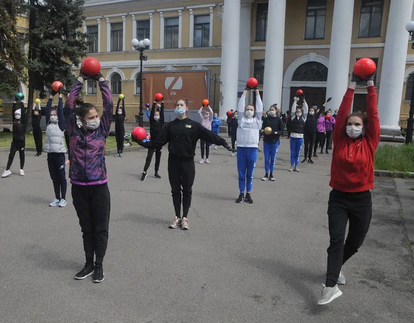 Covid 19コロナウイルス流行の中で保護マスクを着用しているデリギナ学校の体操選手は 6月01 2020にウクライナのキエフ中央部の通りでのトレーニングセッションに参加します — ストック写真
