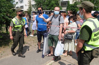 İnsanlar, 21 Haziran 2020 'de Kiev' de patlamanın gerçekleştiği dokuz katlı bir apartmanın yakınında emniyet görevlileriyle konuşuyor.