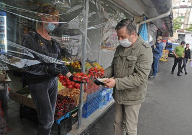 Tıbbi maskeli bir adam 3 Haziran 2020 'de Kiev' deki Vladimir pazarından çilek alıyor..