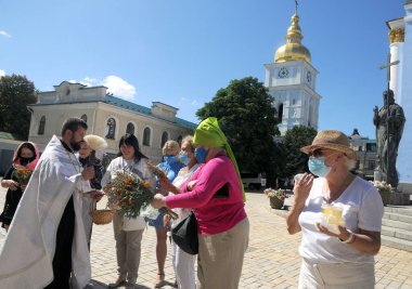14 Ağustos 2020 'de Kiev' deki Aziz Michael Katedrali yakınlarındaki Bal Kurtarıcısı (Makovei) kutlamaları sırasında bir rahip inananlara kutsal su serpti.