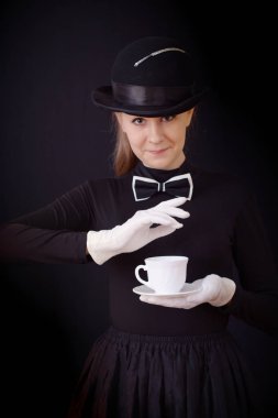Siyah şapka ve siyah takım elbise bir çay çift tutarak yardımcı kadın oyuncu