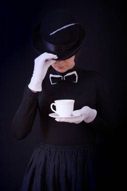 Siyah şapka ve siyah takım elbise bir çay çift tutarak yardımcı kadın oyuncu
