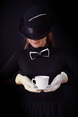 Siyah şapka ve siyah takım elbise bir çay çift tutarak yardımcı kadın oyuncu