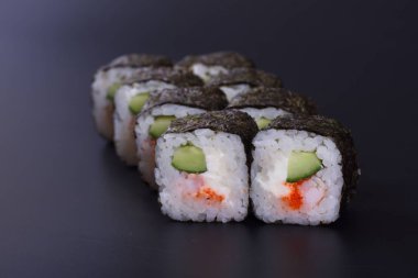 Karanlık bir arka plan üzerinde deniz ürünleri ile Japon rulo