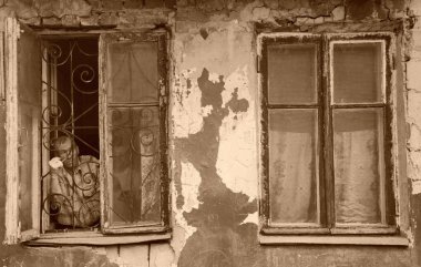 Barnaul,Rusya-1 Mayıs 2019. Fakir bir mahallede eski bir evin penceresinden dışarı bakan bir adam.