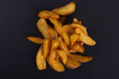 Pişmiş sarı patates dilimleri koyu bir arka plan üzerinde yalan