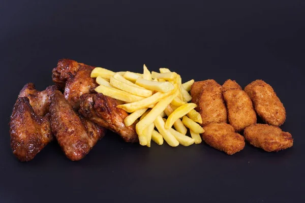 Patates bir garnitür ile kızarmış tavuk kanatları koyu bir arka plan üzerinde yalan