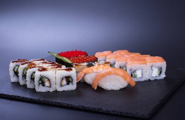 Japon mutfağından deniz ürünleri ve peynirli börekler koyu bir arka planda yatar.