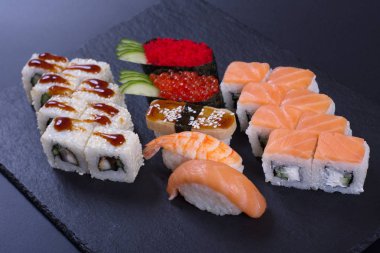 Japon mutfağından deniz ürünleri ve peynirli börekler koyu bir arka planda yatar.