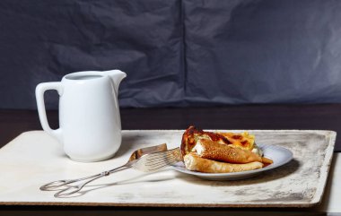 Süzme peynirli ve kuru üzümlü krep ve tabakta süzme peynirli güveç. Mutfak masasında lezzetli bir tatlı ve süt sürahisi.