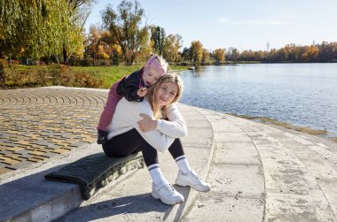 Merhaba Ekim. Anne ve kızı sonbahar şehir parkında yürüyorlar. Ebeveyn ve küçük çocuk dışarıda eğleniyor.