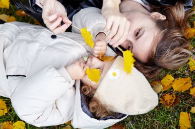 Merhaba Ekim. Anne ve kızı sonbahar şehir parkında yürüyorlar. Ebeveyn ve küçük çocuk dışarıda eğleniyor.