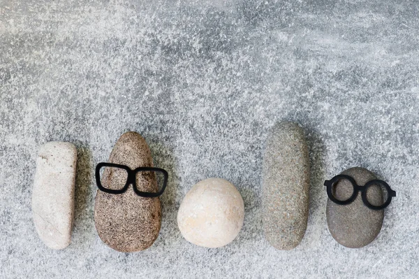 Background with various funny characters of stones on the grey textured surface, copy space
