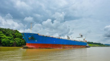 Bir büyük kargo gemisi Panama Kanalı su yolları onun yol yapar. Her iki tarafta asansör kilitleri arasında yeşil yağmur ormanları orman ile kaplı olduğu. Gemi, garip bir şekilde ormanda yelken.