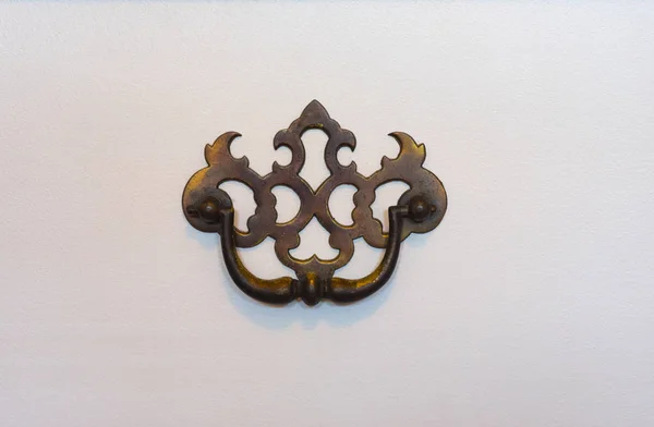 Close up detail Victorian era drawer handle on white dresser.