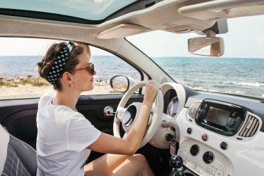 Güneşli deniz kenarında arabada genç kadın