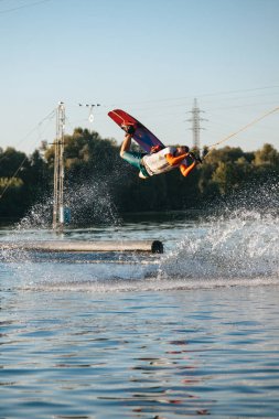 Adam wakeboarding üzerinde aşırı bir atlama yapar, oralarda su sıçramalarına ve su sıçramalarına çoğu.