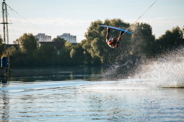Wakeboarder bir göl kenarında bir hile yapmak