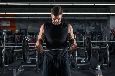 Kaslı adam ile halter, pazı egzersizleri yapıyor spor salonunda egzersiz