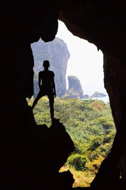 Genç kadın gezgin kayalar ve deniz manzaralı mağarada silüeti