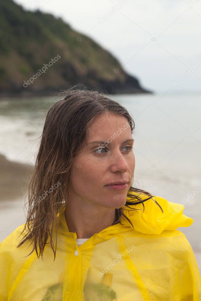 Portrait of woman wearing a yellow raincoat on the beach