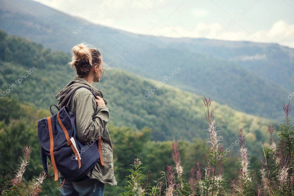 Young woman traveler  with backpack hiking in the mountains, relaxing and enjoying a beautiful nature during vacation .