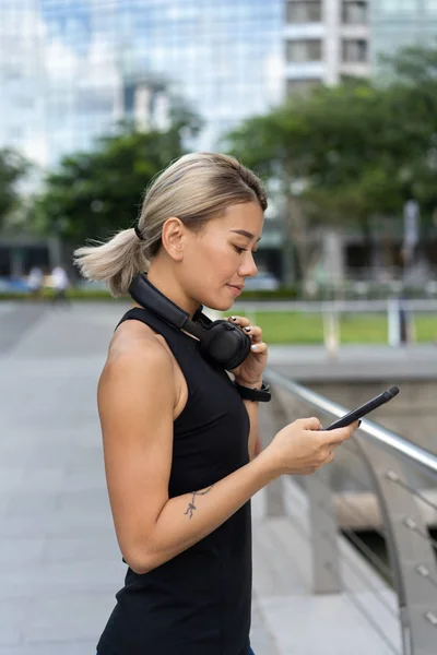 Fitness asiatische Frau überprüft Playlist am Telefon — Stockfoto