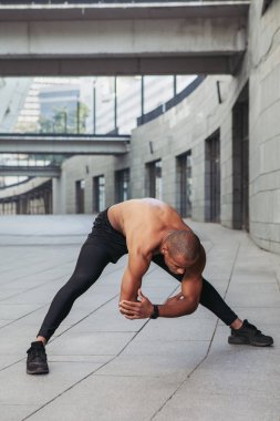 Genç kaslı sporcu antrenmandan önce esneme hareketleri yapıyor.. 