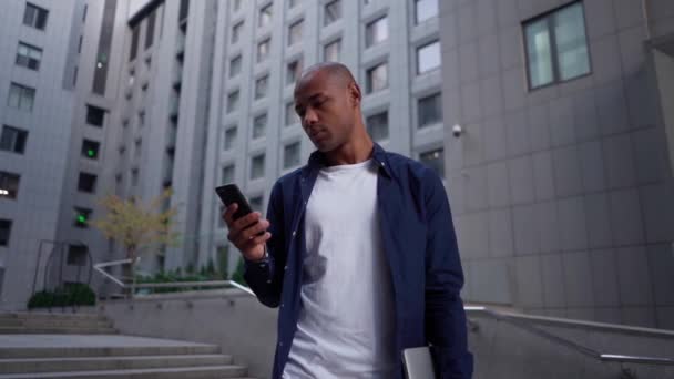 African American Man SMS mensajes de texto utilizando la aplicación en el teléfono inteligente en la ciudad. — Vídeo de stock