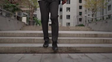 Dizüstü bilgisayarı ve akıllı telefonu olan etnik bir adam sokakta yürüyor.