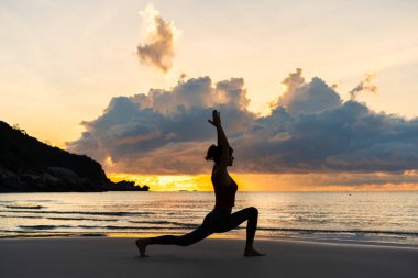 Savaşçı 'nın silueti sahilde güneşin doğuşuna karşı poz veriyor.