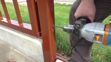 Metal inşaata metal çit döşeyen bir adam. Matkapla ve vidayla metal bir çit yapmak. Elinin ve aletin kapalı konsepti.