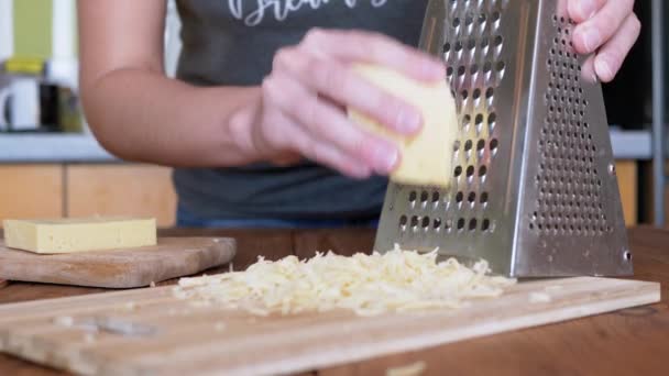 Womans mano strofina formaggio duro su una grattugia di metallo. Cucina casalinga. Primo piano. — Video Stock