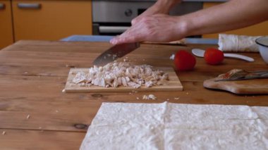 Kadın eli kesme tahtasındaki tavuk filetosunu bıçakla kesti..