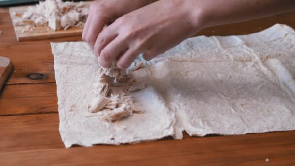 Weibliche Hände legen gekochtes Hühnerfilet auf Lavasch oder Pita-Brot. Wohnküche. — Stockvideo