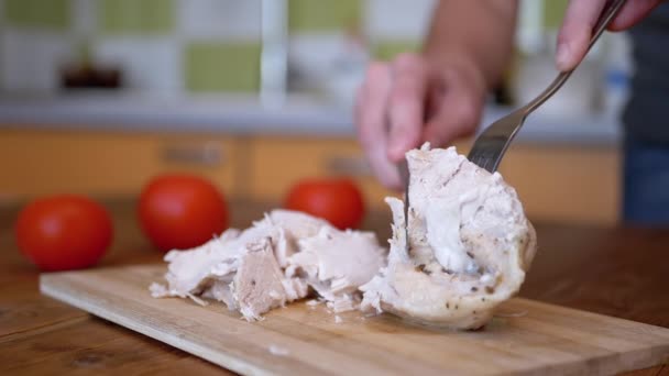 Frau schneidet mit Gabel und Messer gekochtes Hühnerfilet auf Schneidbrett. — Stockvideo