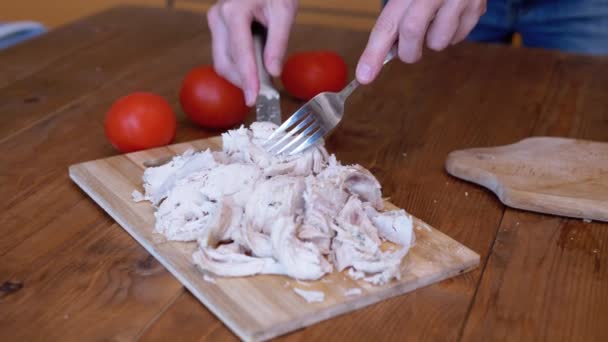 Mujer corta filete de pollo cocido a mano en una tabla de cortar con un tenedor y un cuchillo. — Vídeos de Stock