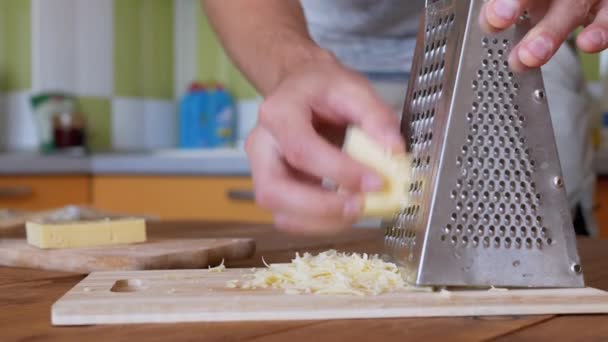 Uomo mano strofina formaggio duro su una grattugia di metallo. Cucina casalinga. Primo piano. — Video Stock