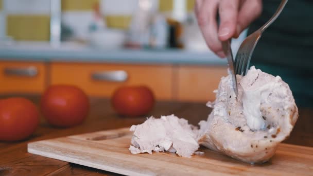 Mujer corta filete de pollo cocido a mano en una tabla de cortar con un tenedor y un cuchillo. — Vídeos de Stock