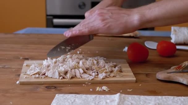 A Mans Hand houpe nožem silně a seká vařené maso na dřevěné desce. — Stock video