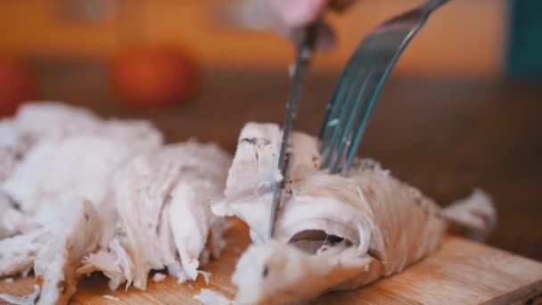 Κοπή βρασμένο κρέας κοτόπουλου σε ένα διοικητικό συμβούλιο με ένα πιρούνι και μαχαίρι. Κοντινό πλάνο. — Αρχείο Βίντεο