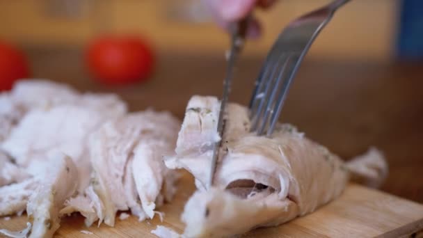 Kadın eli, kesme tahtasındaki tavuk filetosunu çatal ve bıçakla kesti.. — Stok video