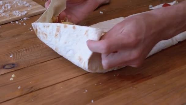 Matlagning kött Shawarma. Man lägger ut grönsaker och rullar snabbt upp en Pita Roll. — Stockvideo