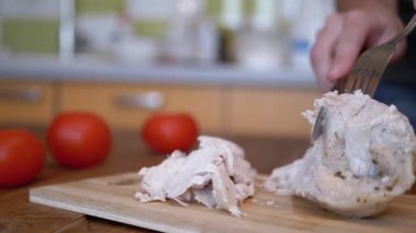 Kadın eli, kesme tahtasındaki tavuk filetosunu çatal ve bıçakla kesti..