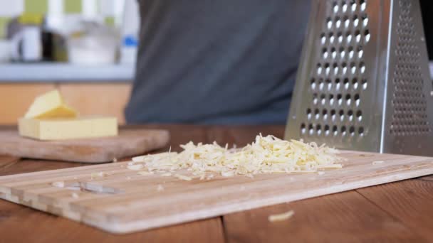 Mans Hand sbriciola formaggio duro su una tavola di legno. Cucina casalinga. Primo piano. — Video Stock