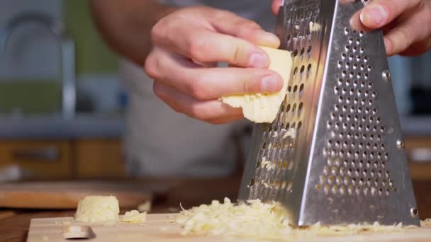 Чоловік натирає твердий сир на металевій решітці. Домашня кухня. Крупним планом . — стокове відео