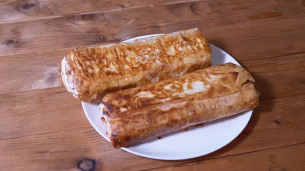 Două Shawarmas suculente crocante sunt servite într-o farfurie de pe masă. Servirea lui Lavash — Videoclip de stoc