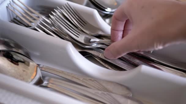 La mano femenina pone una cuchara y tenedores en la caja con cubiertos sucios en la cocina casera — Vídeos de Stock