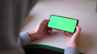 Kadın Elleri Masada Yeşil Dokunmatik ekranlı Akıllı Telefon 'u tutuyor. İnternet